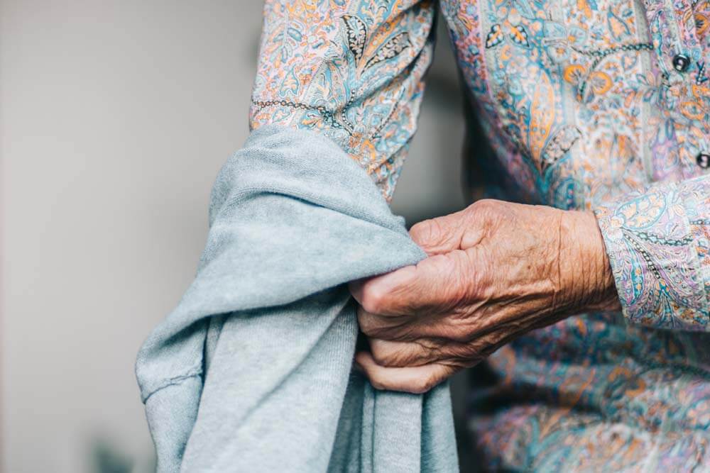 Seniorin beim Anziehen eines Pullovers